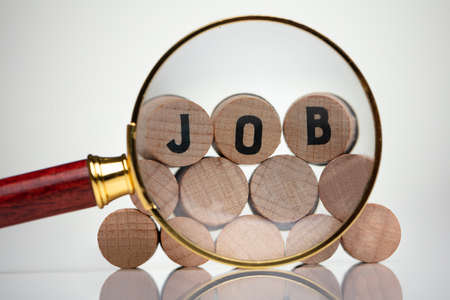 Close-up Of A Job Text Wooden Blocks Behind Magnifying Glass On White Backgroundの写真素材