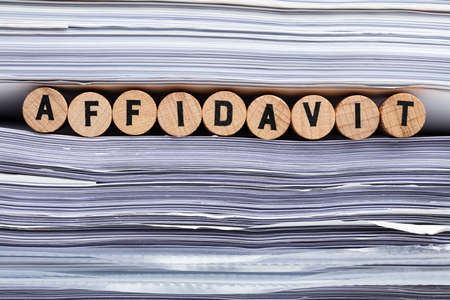 Close-up Of Affidavit Text On Wooden Cork Between Stacked Data