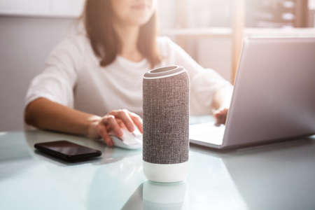 Smiling Young Woman Using Voice Assistant In Office