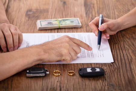 Judge Assisting Client In Filling Contract Form With Pair Of Golden Ringsの写真素材