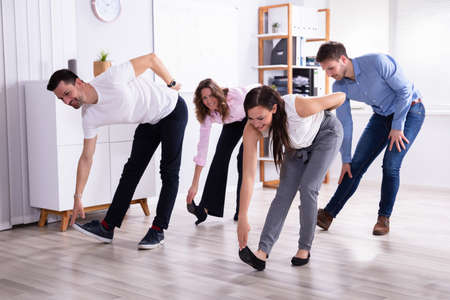 Group Of Happy Young Businesspeople Doing Stretching Exercise In Officeの写真素材