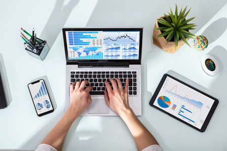 Close-up Of Businesswoman Analyzing Graph On Laptop At Workplace In The Officeの写真素材