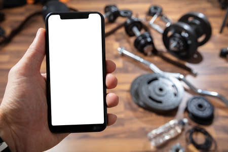 Close-up Of Person's Hand Holding Cellphone With Blank Screen In Gymの写真素材