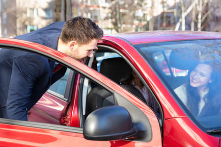Smiling Young Man Talking With A Lady Sitting Inside Car