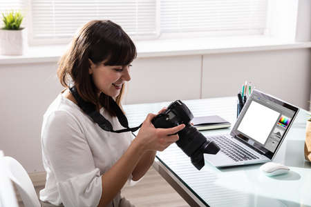 Close-up Of An Editor Looking At Photograph In DSLR Camera At Workplaceの写真素材