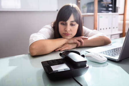 Sad Young Businesswoman Waiting For A Call On Landline