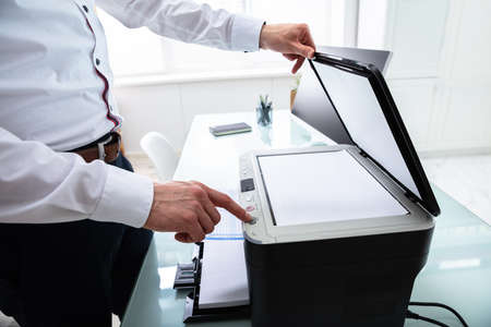 Close-up Of Businessman Pressing Printer's Button In Officeの写真素材