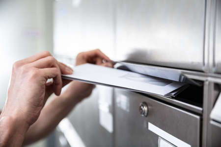 Close-up Of Human's Hand Inserting Letters In Mailboxの写真素材