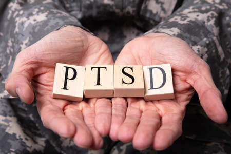 Close-up Of Male Soldier In Military Uniform Holding Wooden Cubes With PTSD Textの写真素材