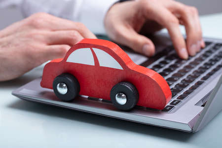 Close-up Of A Businessman's Hand Using Laptop With Red Car On Keypad