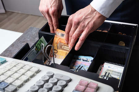 An Overhead View Of Cashier's Hand Taking Banknote From Opened Tillの写真素材