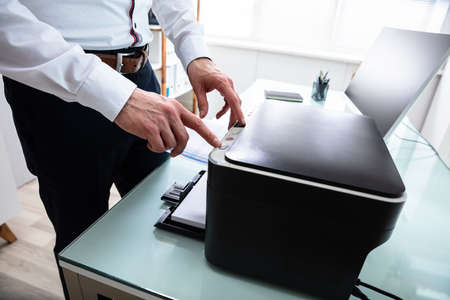 Close-up Of Businessman Pressing Printer's Button In Officeの写真素材
