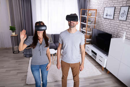 Young Couple Using Virtual Reality Device At Homeの写真素材