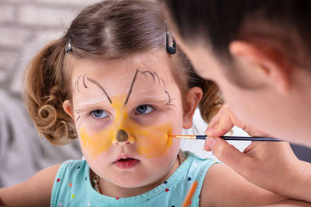 Painting The Face Of A Little Girls With Color Brush