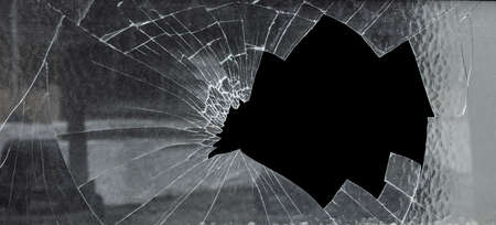 Broken Cracked Glass With Big Hole Against Black Background