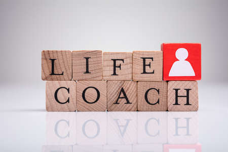 Red Human Figure Block Next To Word Life Coach On Wooden Block