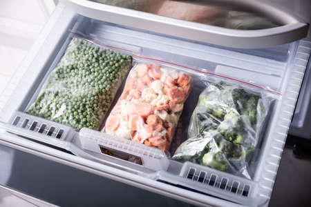 An Overhead View Of Frozen Vegetables In Plastic Bag Over Refrigerator Trayの写真素材