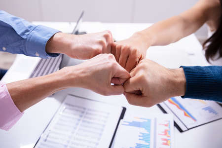 Close-up Of Businesspeople Making Fist Bump Over Deskの写真素材