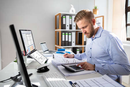 Businessperson Calculating Invoice With Computer On Deskの写真素材