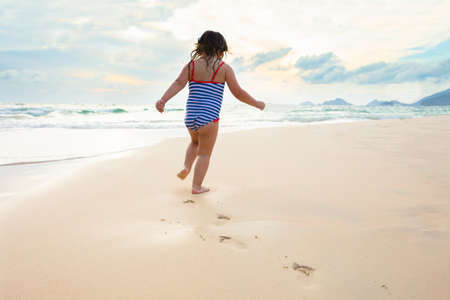 Little Girl In Bikini Running On The Idyllic Sandy Beach Near The Coastの写真素材