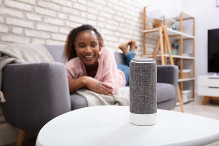 Woman Using Voice Assistant Speaker On Tableの写真素材