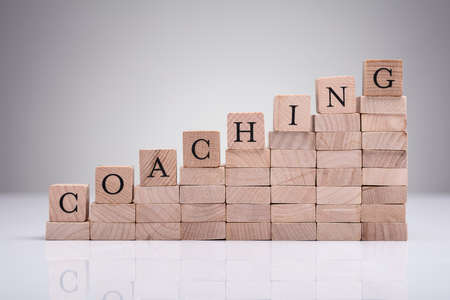 Close-up Of Coaching Word On Wooden Blocks Over Reflective Deskの写真素材