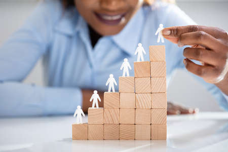 Close-up Of White Human Figures Leading On Top Of Wooden Blocks In Officeの写真素材