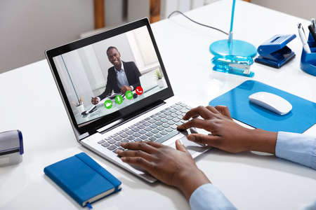 Close-up Of A Businessperson's Videoconferencing With Male Colleague On Laptopの写真素材