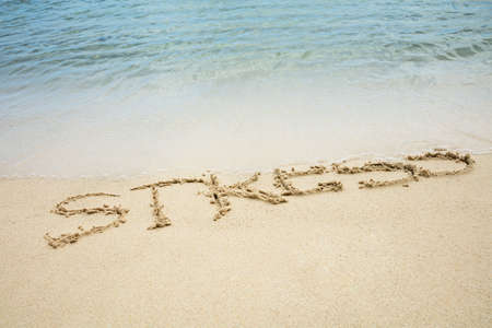 An Overhead View Of Stress Word Written On Sand Wash With Sea Waves On Beach