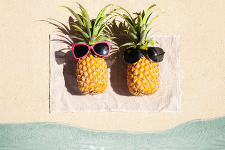 An Overhead View Of Two Pineapple Lying On Towel On The Beach