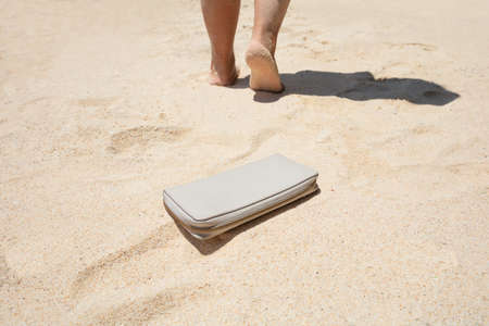 Close-up Of A Woman Lost A Purse With Money On The Sandy Beachの写真素材