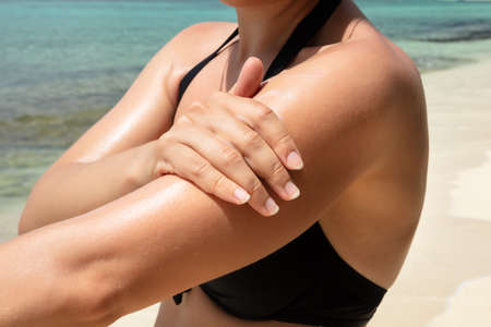 Close-up Of A Woman Applying Sunscreen Lotion On Her Arm At Beach