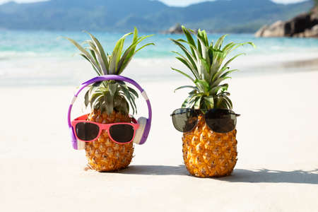 Close-up Of Pineapple With Headphone And Sunglasses On Sand At Beachの写真素材