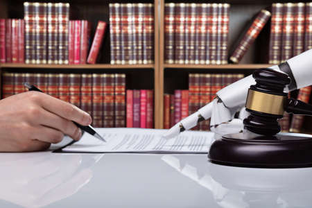 Robotic Hand Assisting Person For Signing Document Over Reflective Desk In The Courtroomの写真素材