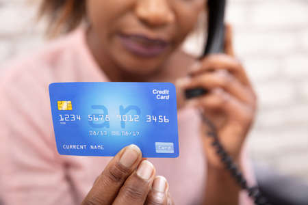 Close-up Of A African Woman With Credit Card Using Landline Phoneの写真素材