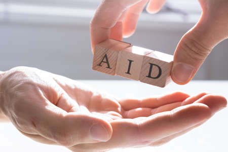 Close-up Of Person's Hand Giving Aid To Other Person