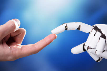 Robot Touching Man's Index Finger Against Digital Backdropの写真素材