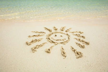Close-up Of Smiling Sun Drawn On Sand Near The Sea At Beachの写真素材
