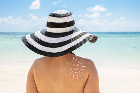 Rear View Of A Young Woman With Smiling Sun Drawn On Her Back At Beach
