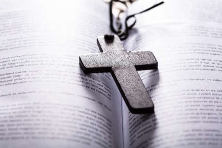 Close-up Of Opened Holy Bible With Wooden Crossの写真素材