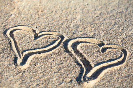 Close-up Of Two Hand Drawn Hearts On Sand At Beach
