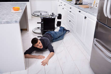 Young Disabled Man Fallen Down From Wheelchair In Kitchenの写真素材
