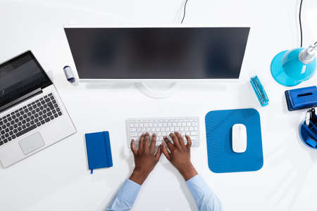 An Elevated View Of A Businessperson's Hand Working On Computer With Blank Screenの写真素材
