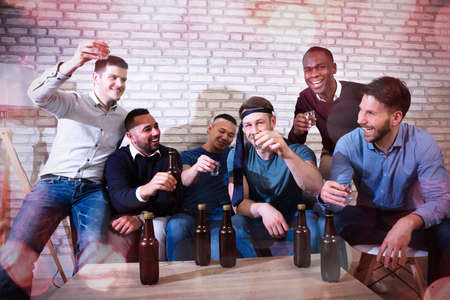 Group Of Cheerful Young Men Toasting With Tequila At A Nightclub