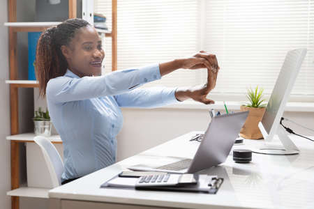Side View Of A Young Businesswoman Stretching Her Hand In Office