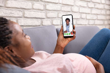 Close-up Of Pregnant Woman Video Calling Her Doctor On Mobilephoneの写真素材