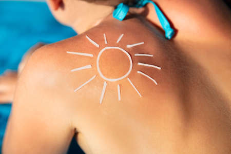 An Overhead View Of Sun Drawn On Woman's Back With Sunscreen Lotionの写真素材