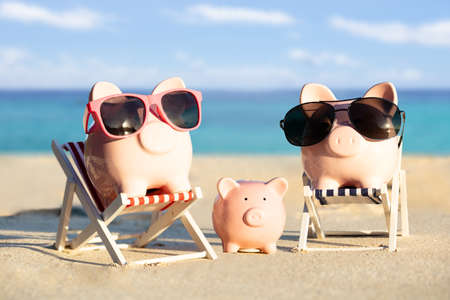 Front View Of A Pink Piggybank Family With Sunglasses On Sand At Beachの写真素材