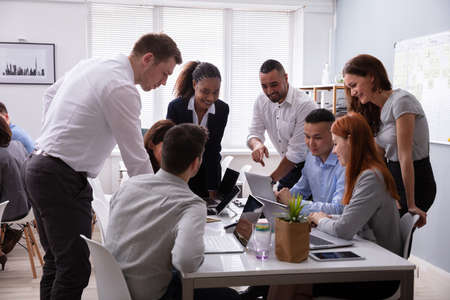 Group Of Young Diverse Business People Working And Communicating While Sitting At The Office Desk