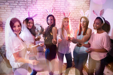 Beautiful Women Drinking Tequila Shots Wearing Feather Boa And Bunny Ear Hair Bandの写真素材